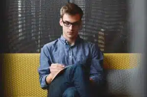 Mies istuu keltaisella sohvalla kirjoittaa muistilehtiöön ajatuksia tulevasta yrittäjyydestä.